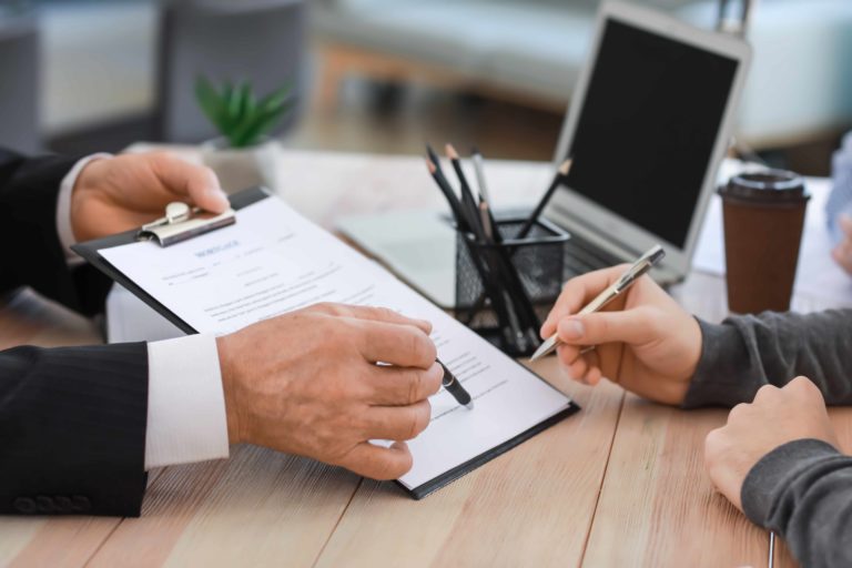 A person signing a document at a desk.