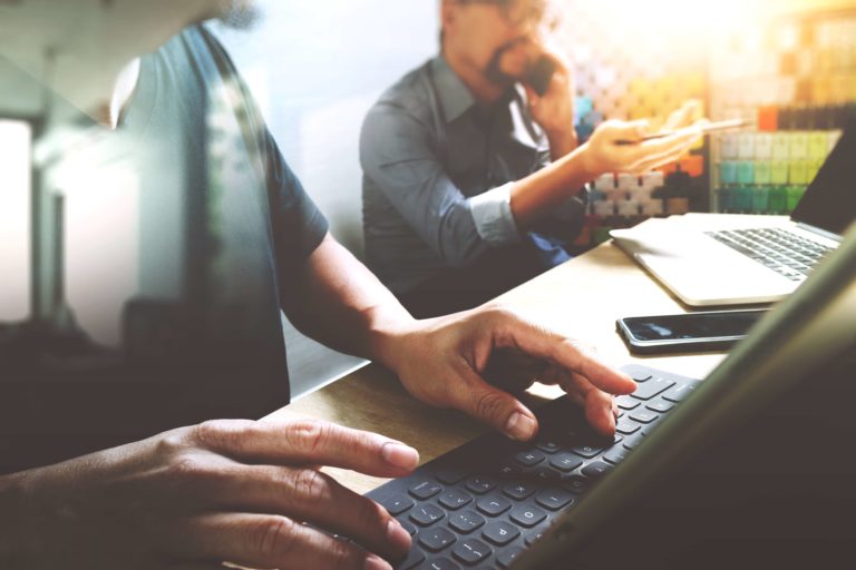 A man is typing on a laptop while sitting at a table.