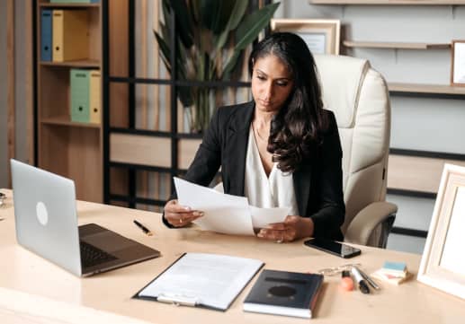 A woman sitting at a desk with papers and a laptop needs attorney in Los Angeles