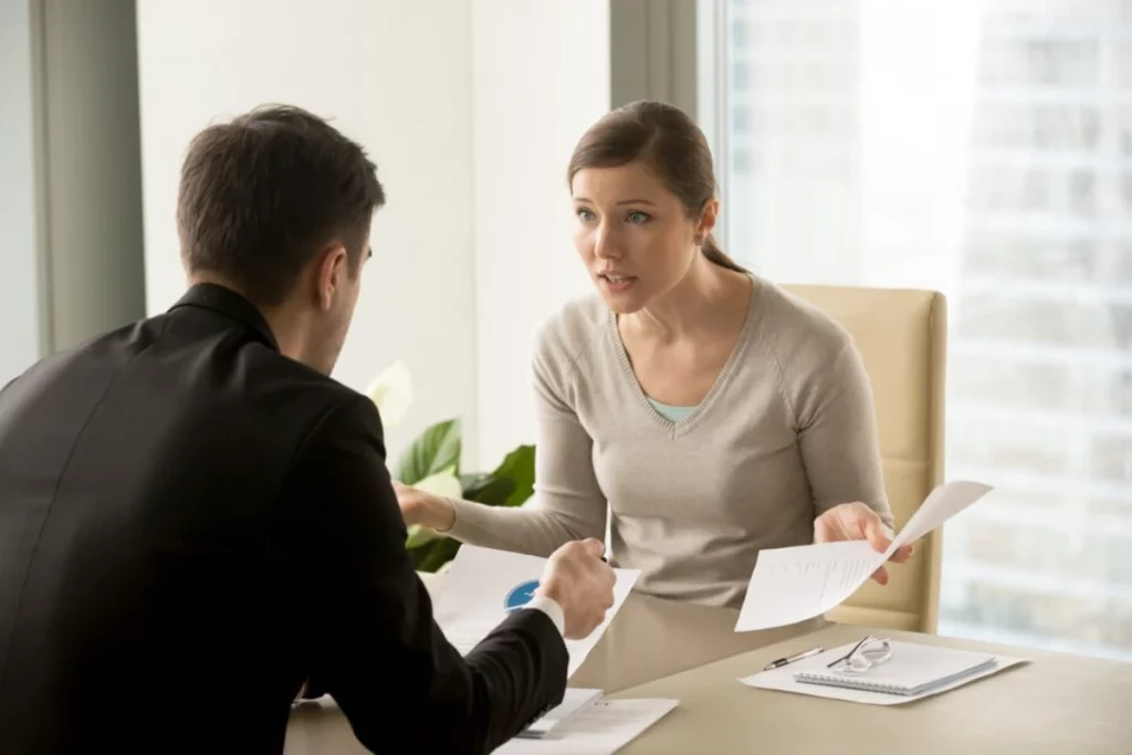 A man and woman talking at a desk in an office.