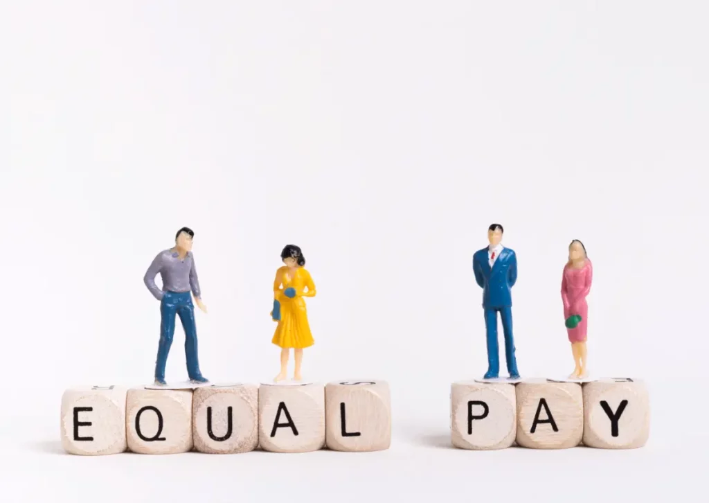 A group of people standing next to a block with the word equal pay.
