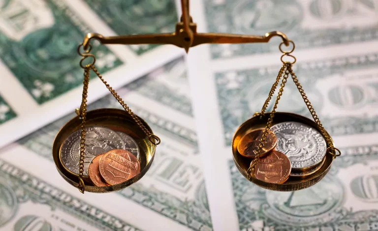 A balance scale with coins, including pennies and quarters, is placed over scattered dollar bills, symbolizing the delicate nature of financial disputes often seen in FINRA arbitration.