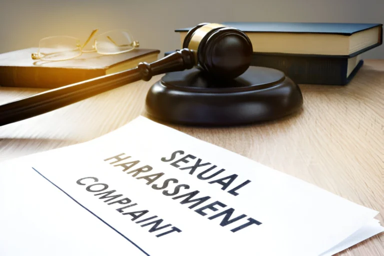 A gavel rests on a desk beside a document titled "Sexual Harassment Complaint" with a book and glasses in the background.